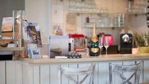 A bar area with a bottle of champagne, glasses, and a book titled "GOLVEN". - Hotel Kijkduin (Domburg)