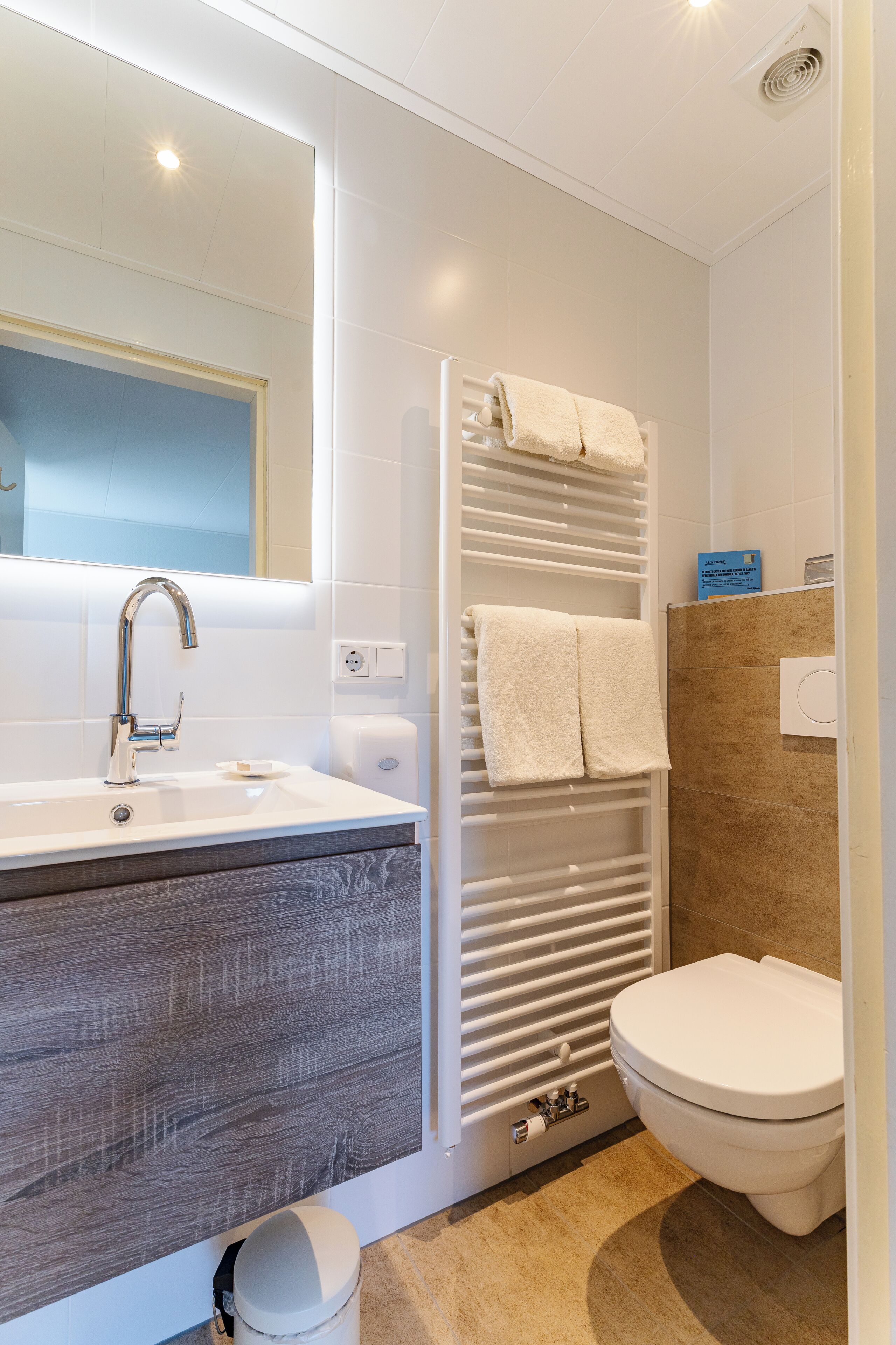 A modern bathroom with a sink, mirror, towel rack, shower, and toilet.
