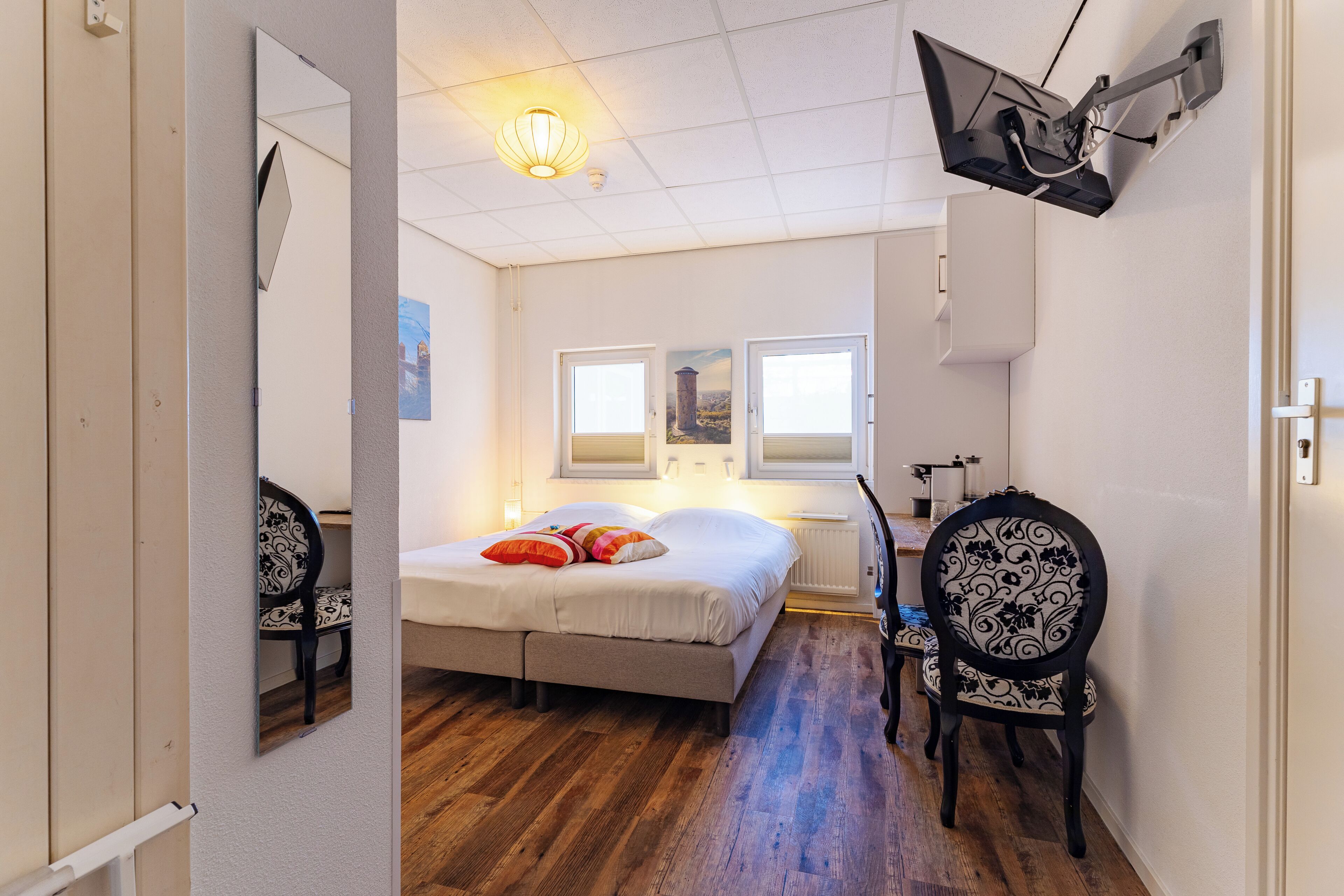 Un dormitorio con cama, una silla, un escritorio y ventana.
