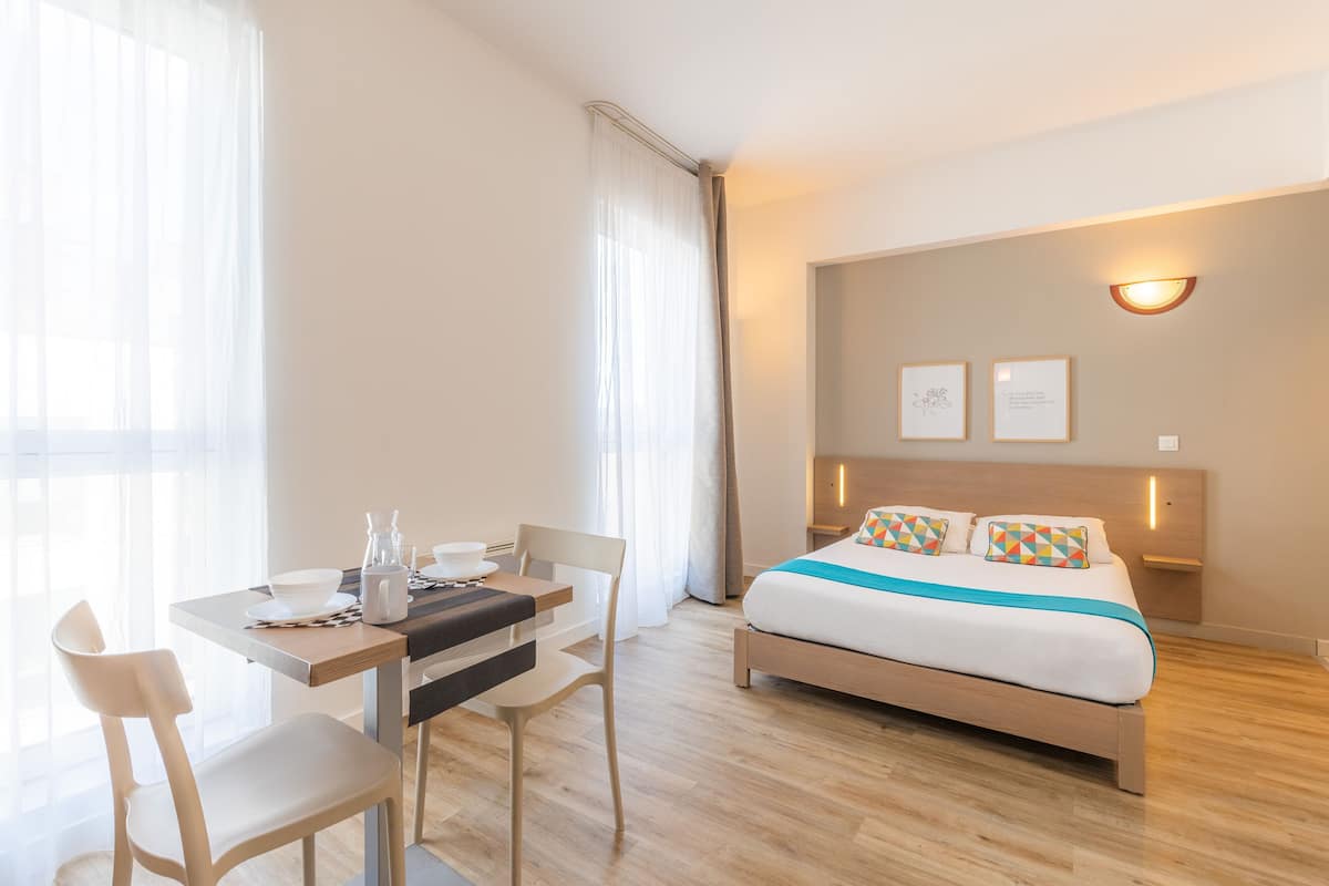 Ein modernes Hotelzimmer mit Bett, Nachttisch und einem Essbereich mit Stühlen und Tisch.