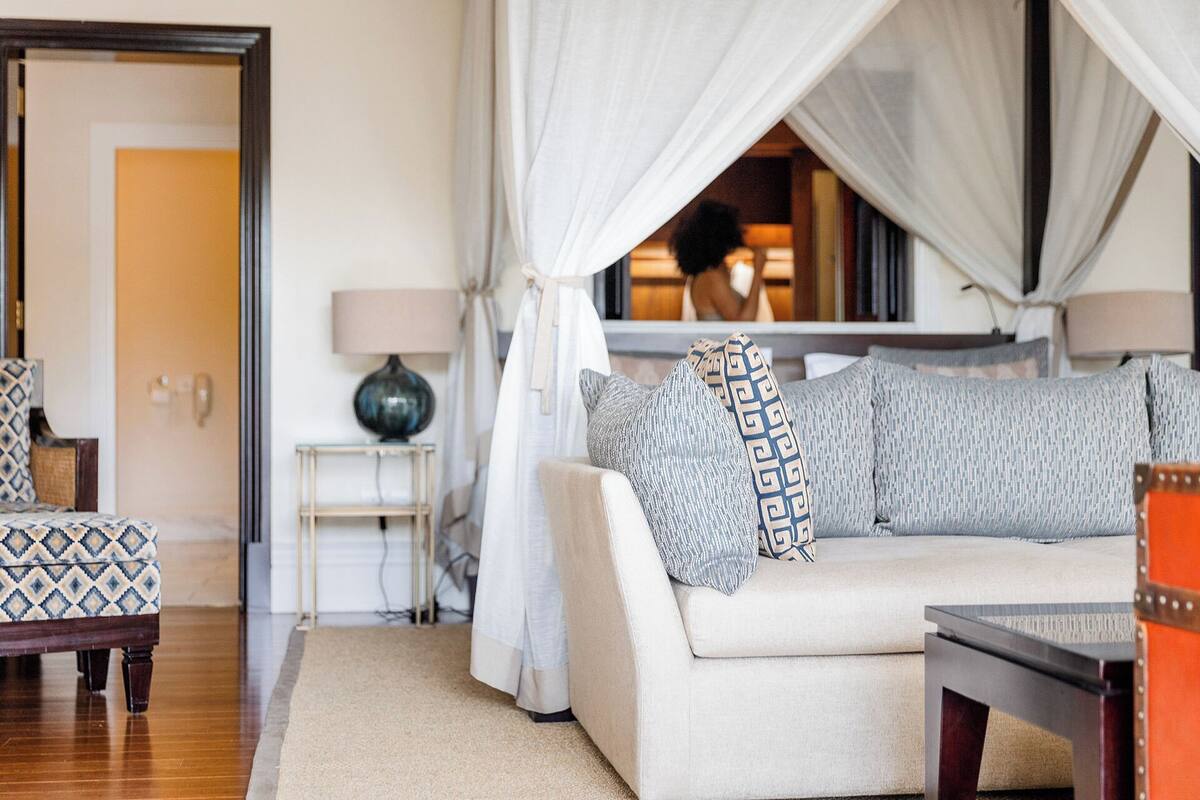 Une pièce confortable avec un canapé, une petite table, une lampe et un lit à baldaquin.