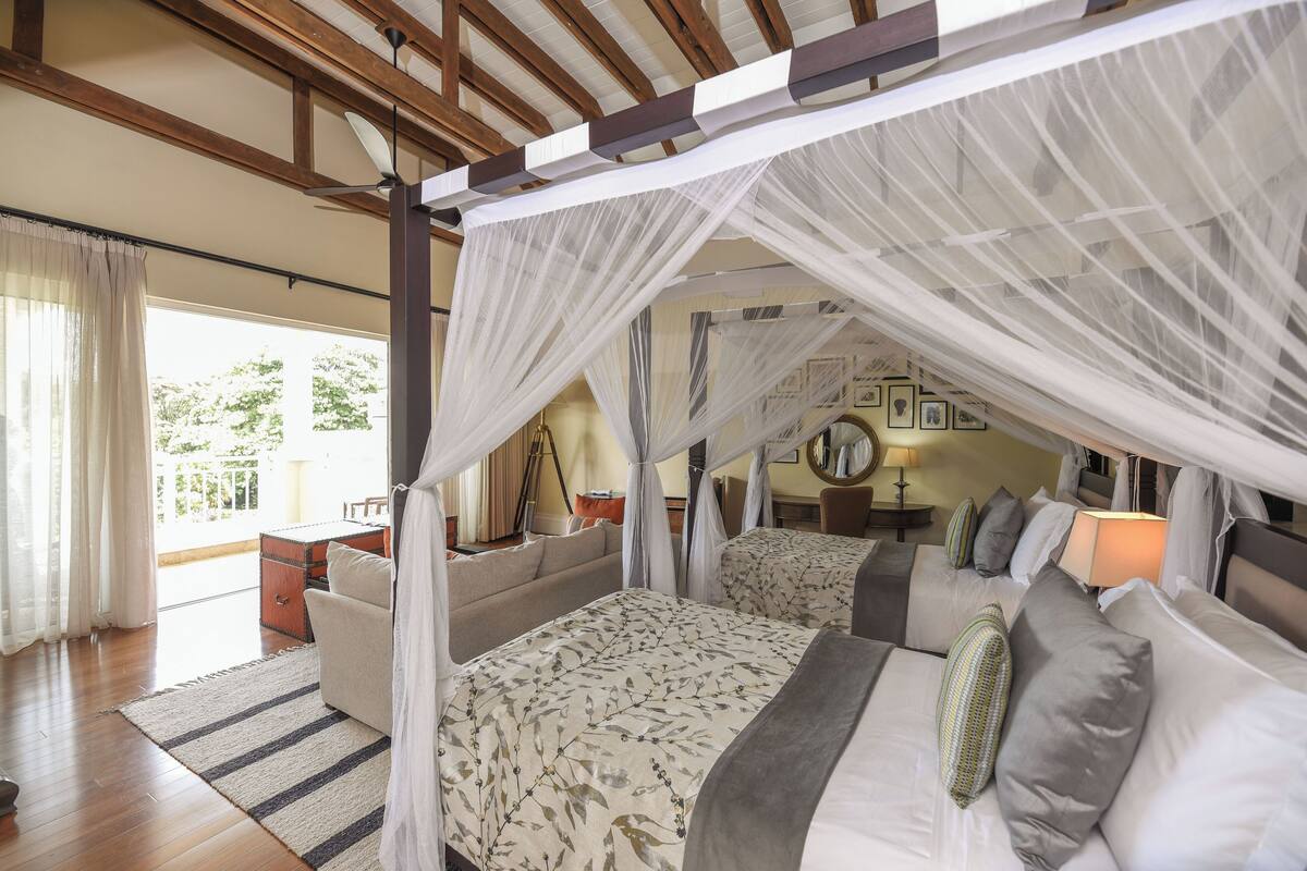 Une chambre avec un lit à baldaquin, un canapé et une vue sur l’extérieur.