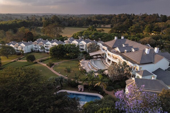 A large resort with multiple guest buildings, a swimming pool, and landscaped gardens.