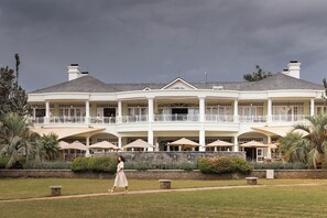 A large, multi-story building with a white exterior, multiple balconies, and outdoor seating areas.