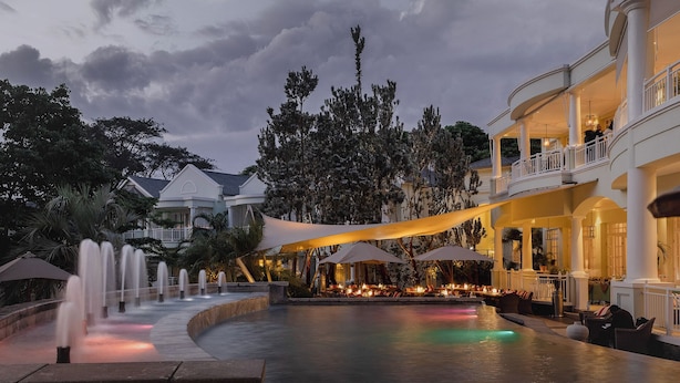 A luxurious hotel with a water feature, outdoor seating, and a covered dining area. - Hemingways Nairobi (Nairobi)
