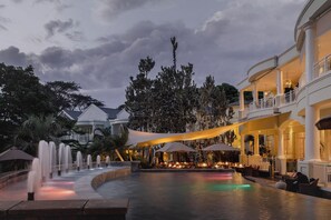 Ein luxuriöses Hotel mit Wasserspiel, Außenbereich mit Sitzgelegenheiten und überdachter Essecke.