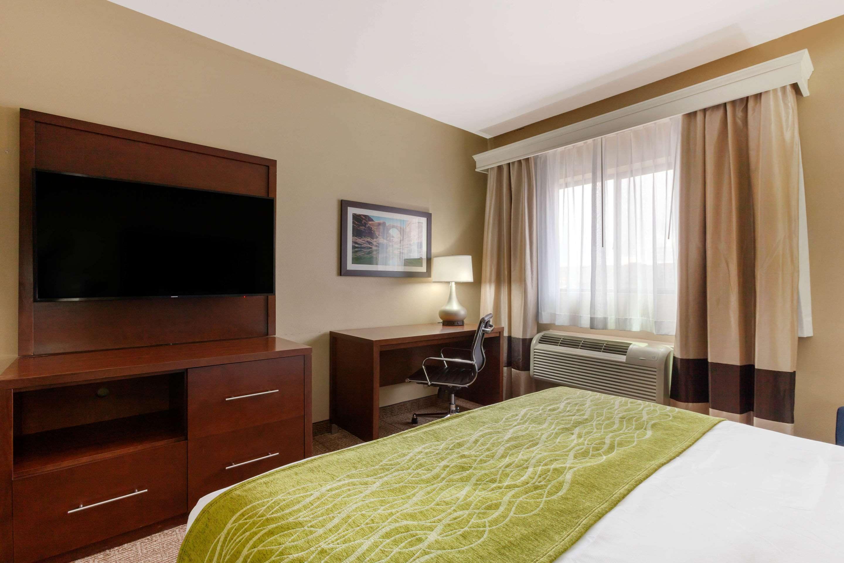 A hotel room with a bed, a desk, a television, a chair, and a window with curtains.