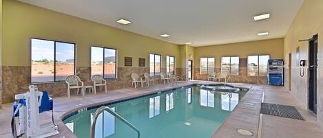 A swimming pool with a sunbathing area, chairs, and a lifeguard stand.