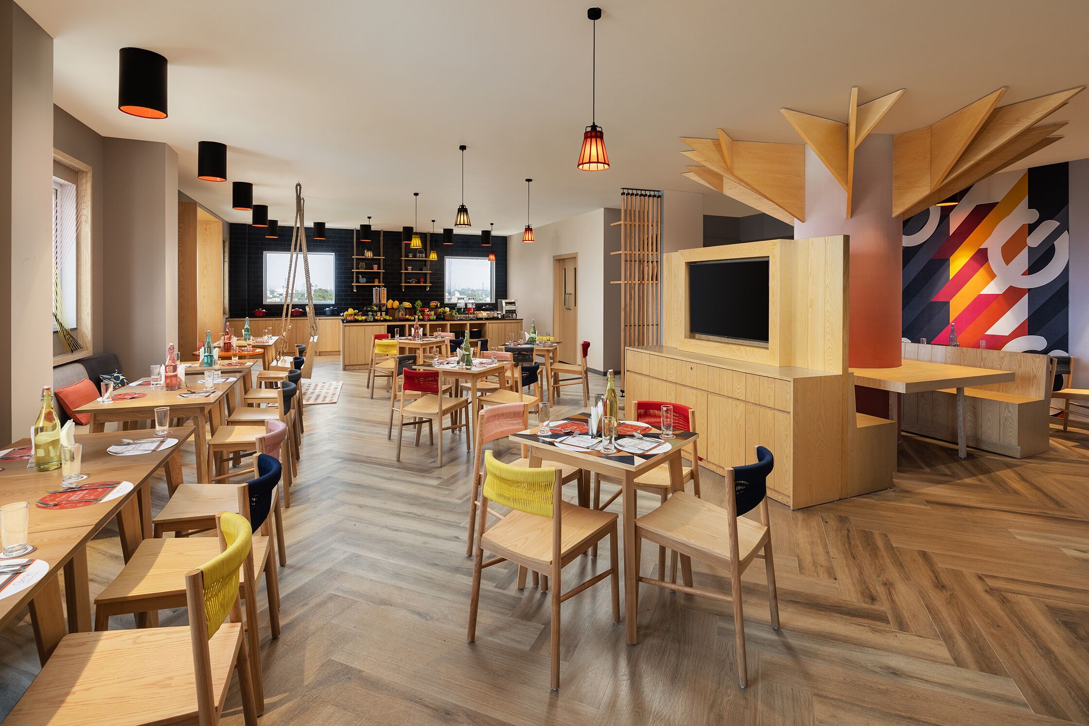 Un comedor amplio con varias mesas y sillas de madera, una zona de bar con un televisor grande y un diseño moderno con detalles de madera e iluminación colgante.