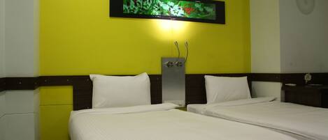 Habitación de hotel con dos camas, un televisor montado en la pared y una mesita de noche con lámpara.