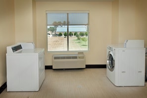 A laundry room with two washing machines and an air conditioning unit.