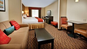 A hotel room with a bed, a sofa, a desk, and a TV.