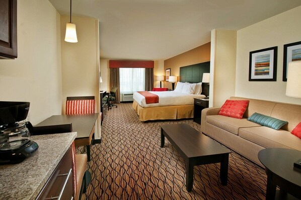 Hotelkamer met een bed, een sofa, een salontafel, een bureau met koffiezetapparaat en een televisie.