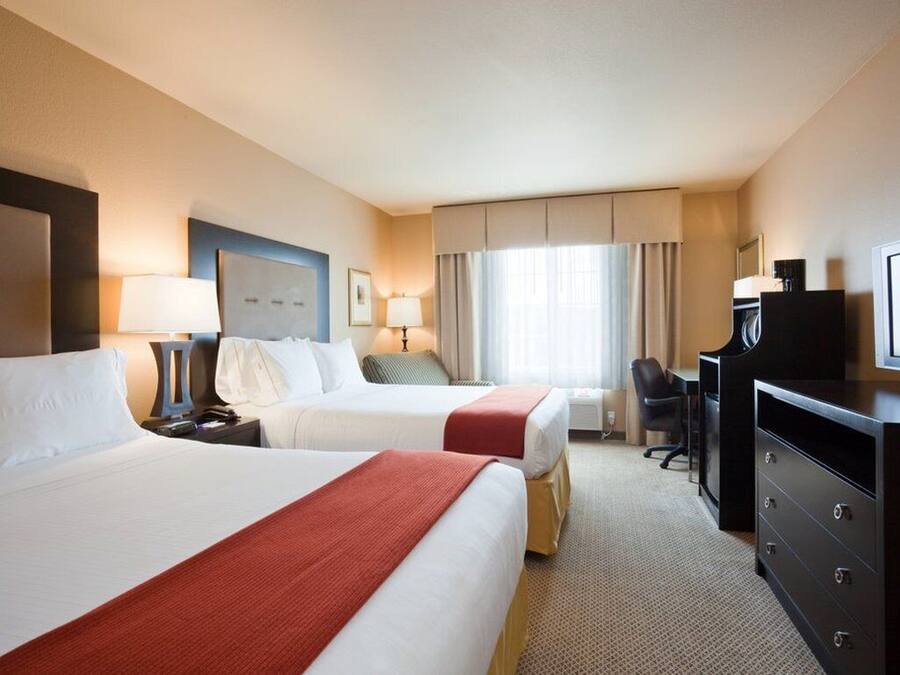 Une chambre d’hôtel avec deux lits, un bureau, une télévision et une commode.