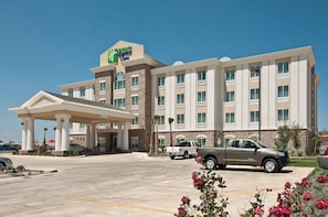 A Holiday Inn Express hotel with a covered entrance, a parking lot, and a pickup truck parked in front.