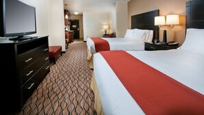 A hotel room with two beds, a TV, a desk, and a lamp.