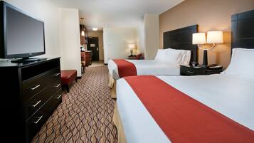 A hotel room with two beds, a TV, a desk, and a lamp.