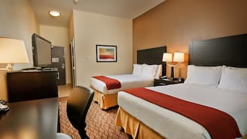 A hotel room with two beds, a desk, and a chair.