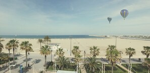 A beach with palm trees, a lifeguard tower, and a clear sky. - Hotel Boutique Sabbia Valencia (Valencia)