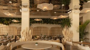 A restaurant with round tables, wicker chairs, and hanging pendant lights. - Hotel Boutique Sabbia Valencia (Valencia)