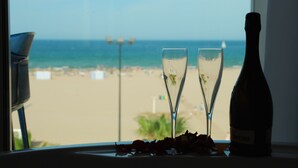 A window view of a beach with two champagne flutes and a bottle on a windowsill. - Hotel Boutique Sabbia Valencia (Valencia)