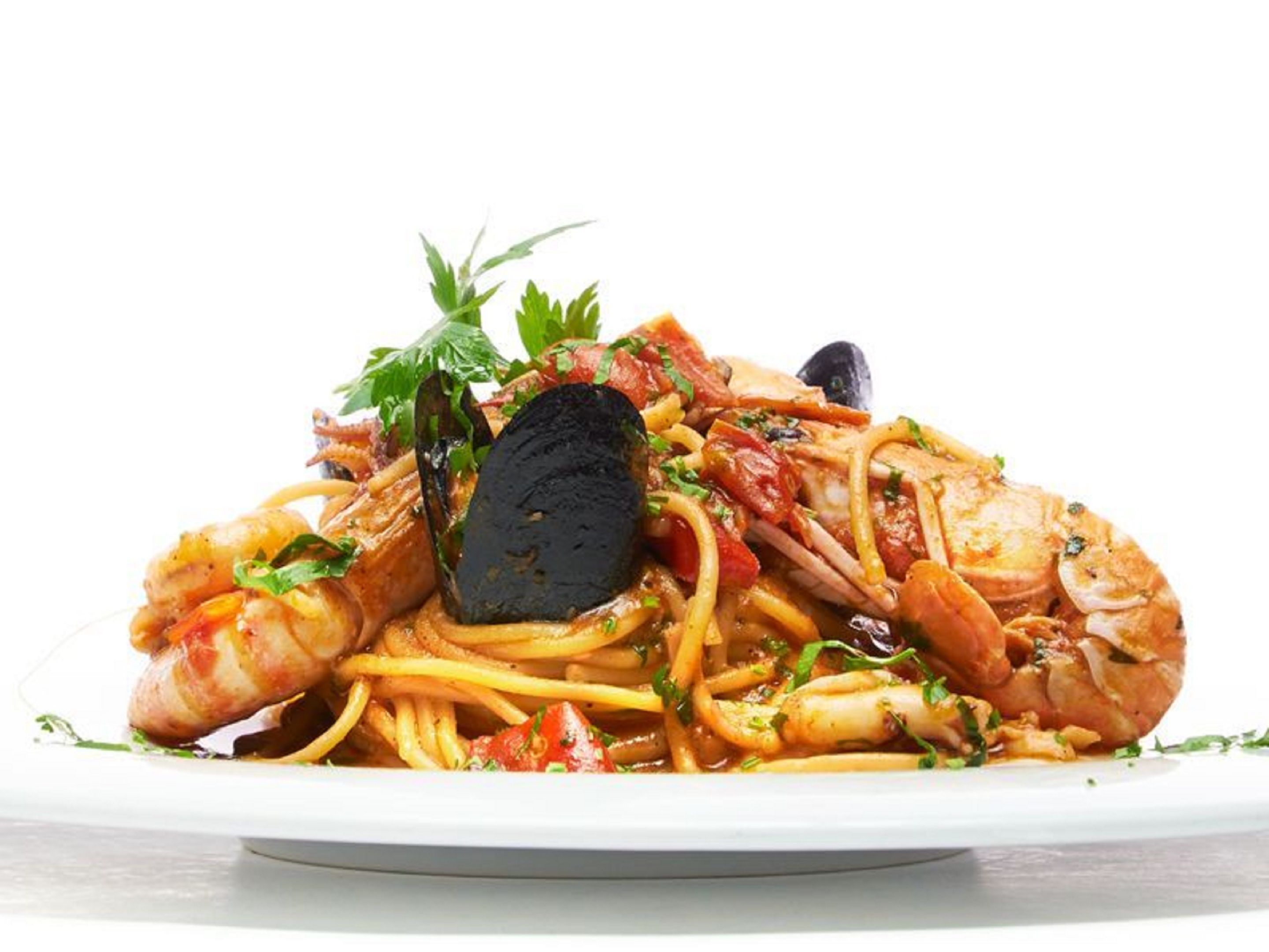 A seafood pasta dish with mussels, shrimp, and herbs on a white plate.