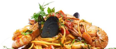 A seafood pasta dish with mussels, shrimp, and herbs on a white plate.