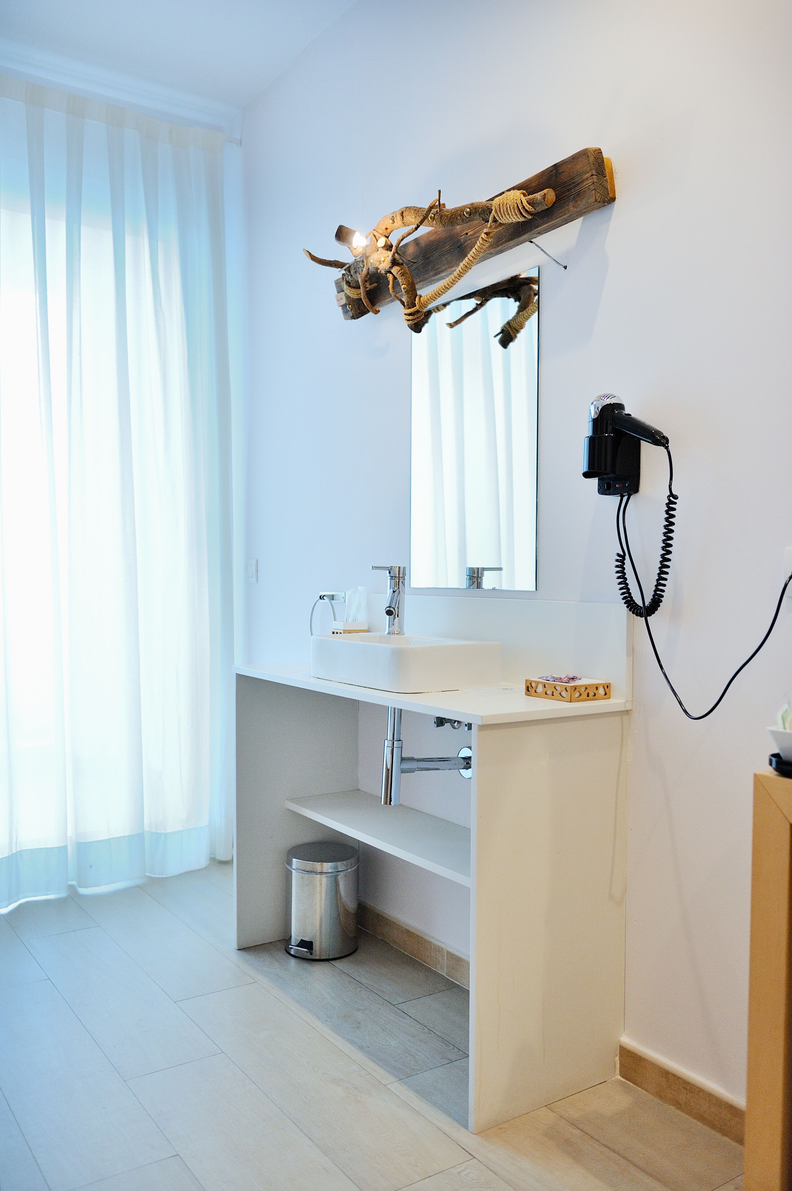 Ein Badezimmer mit Waschbecken, Spiegel und einem fest montierten Fön.