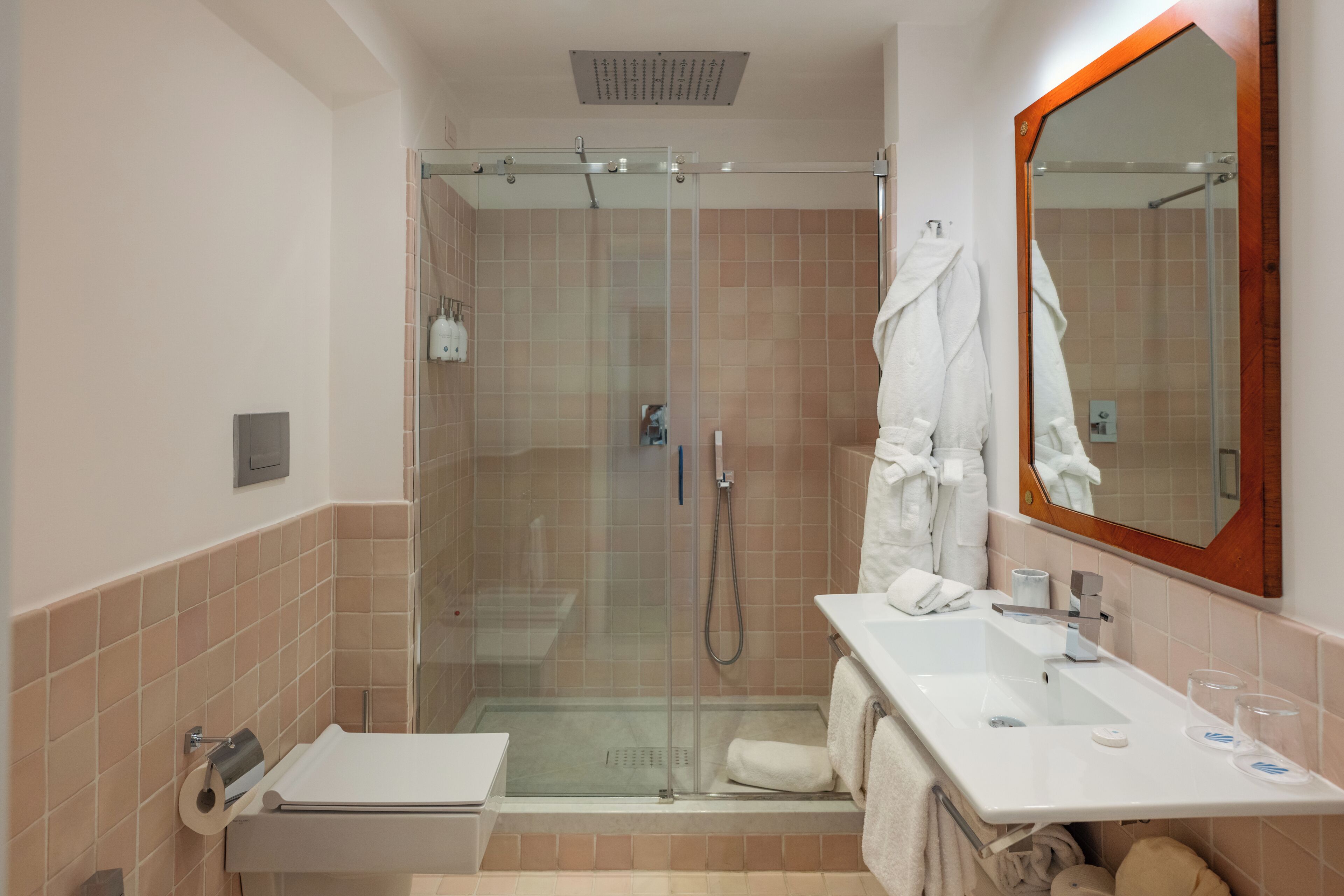 A bathroom with a glass-enclosed shower, a sink with a mirror, and towels.