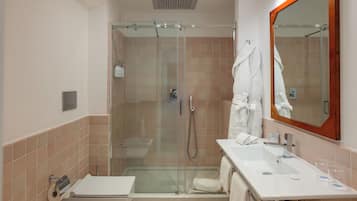 A bathroom with a glass-enclosed shower, a sink with a mirror, and towels.