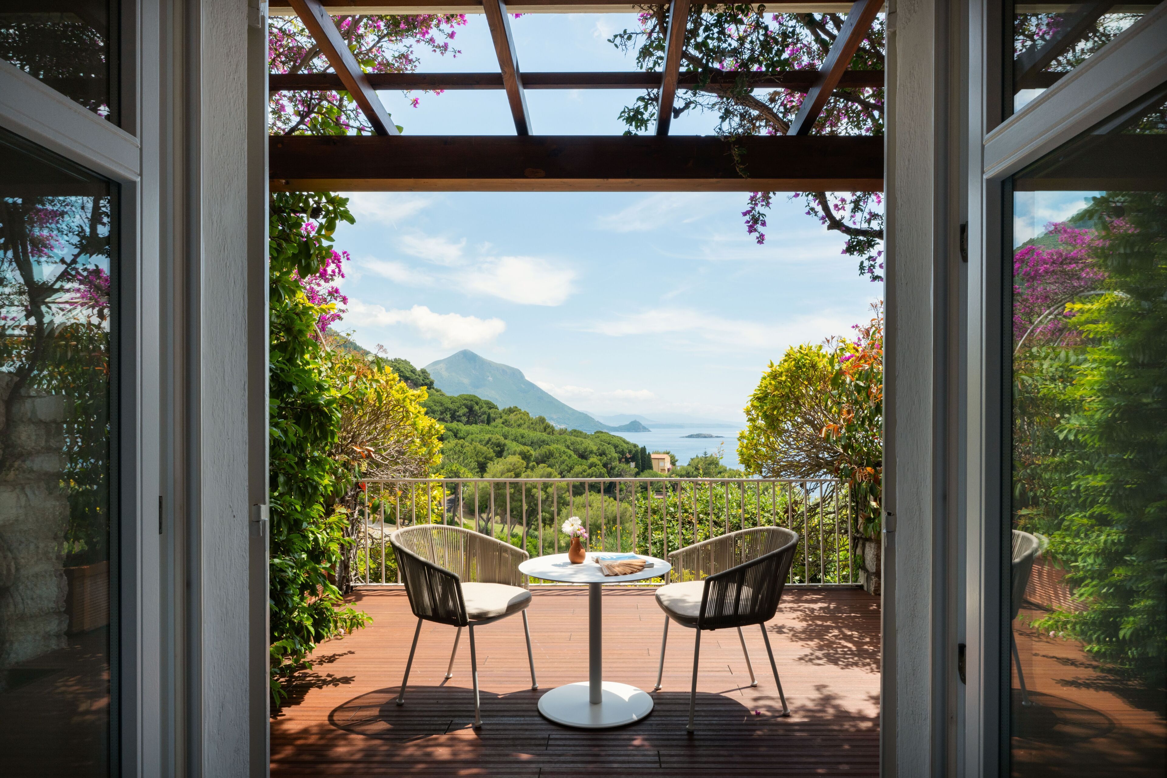 Un balcon avec une table et des chaises, donnant sur un paysage montagneux.
