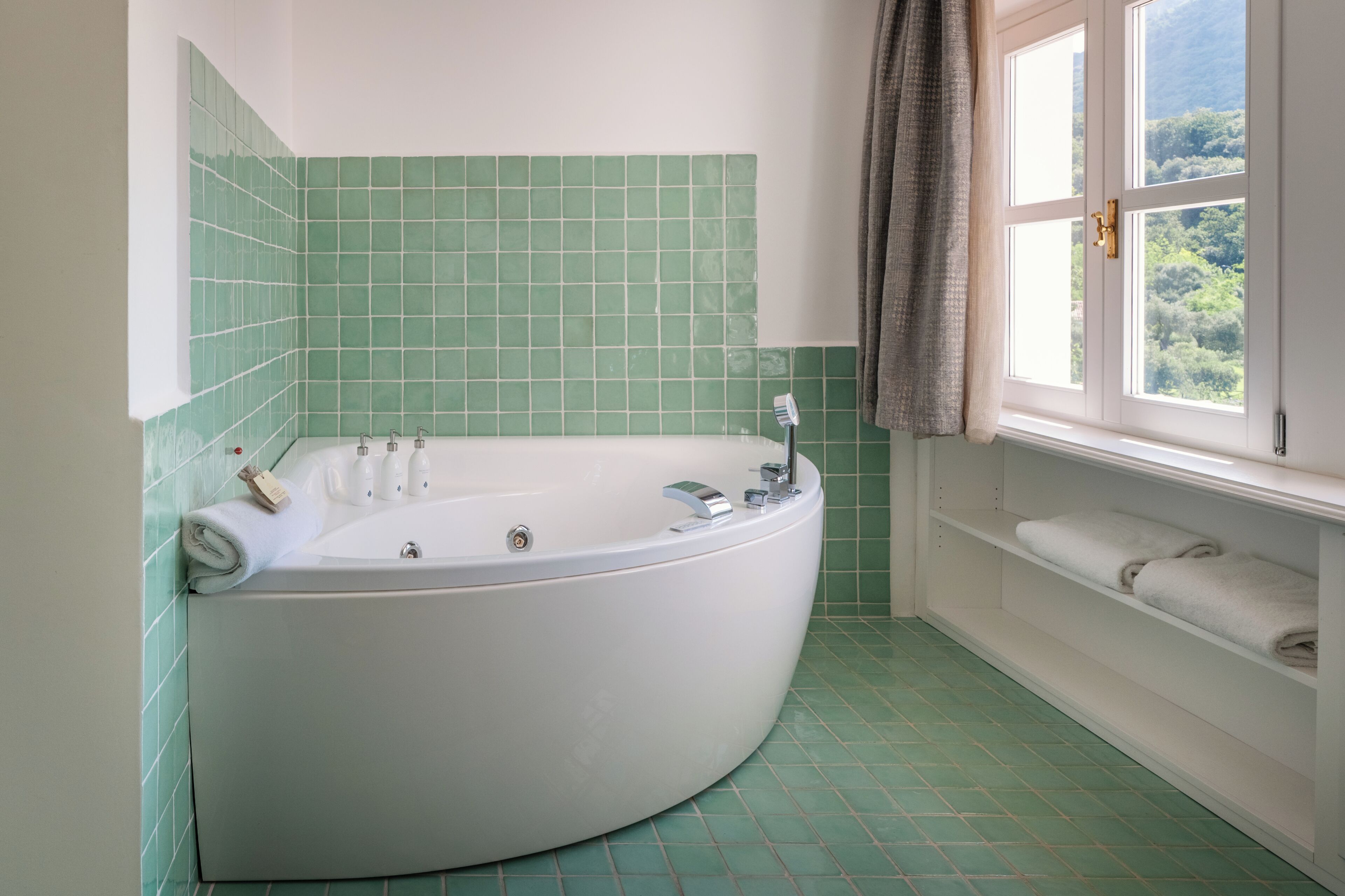Une salle de bain avec une baignoire sur pieds, une fenêtre donnant sur un beau paysage et une étagère avec des serviettes.