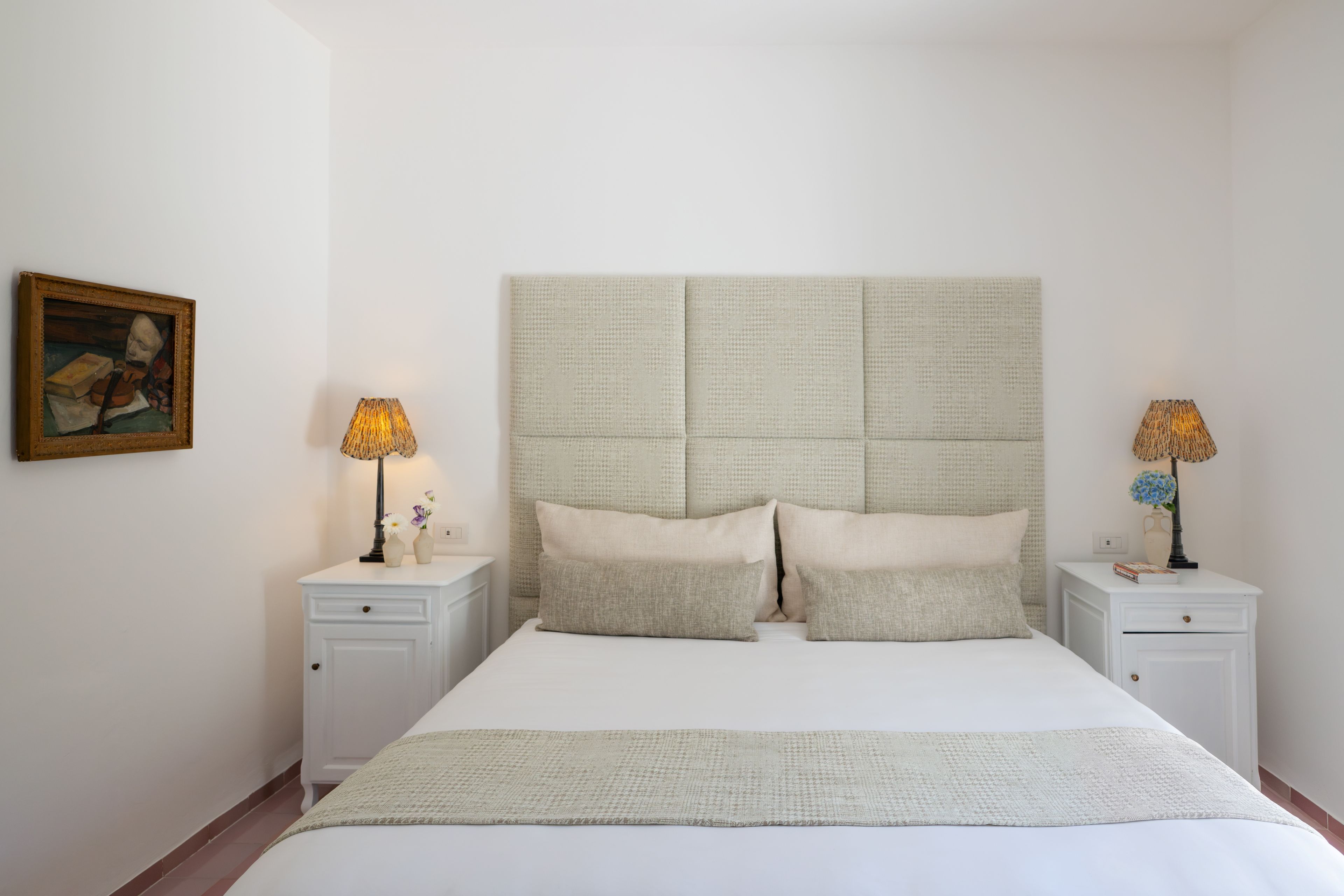 Una camera da letto con un letto grande, due comodini, un tavolino, un quadro e due lampade.