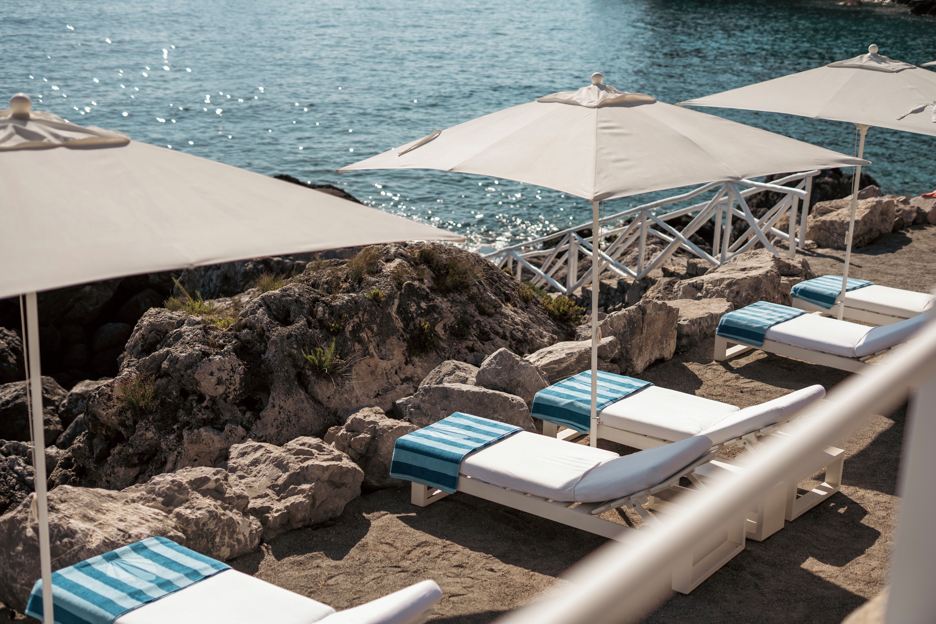 A beachside lounge area with sunbeds and umbrellas.