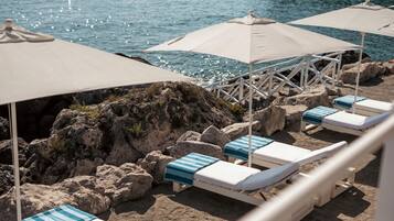 A beachside lounge area with sunbeds and umbrellas.