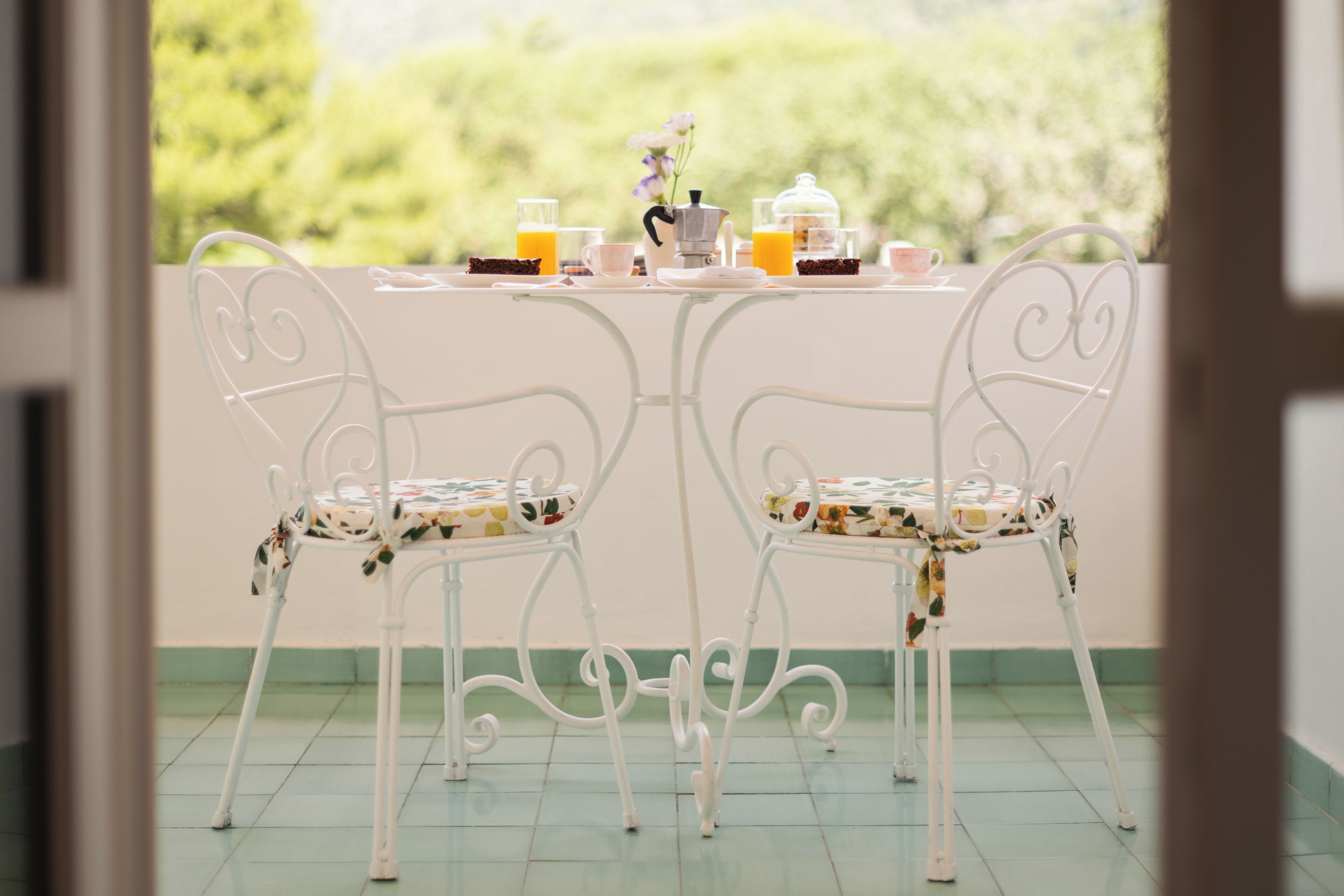 A dining table with chairs, a coffee pot, and a glass of orange juice.