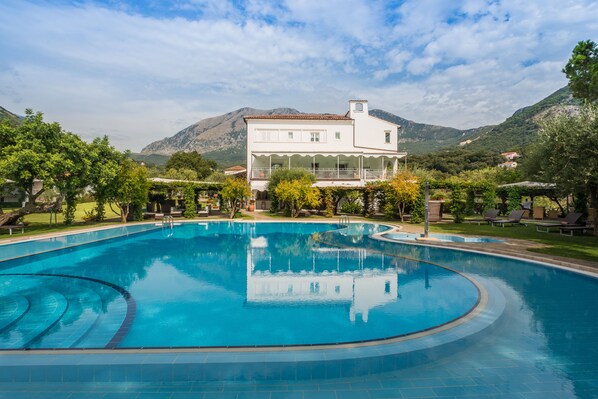 En säsongsöppen utomhuspool, parasoller och solstolar