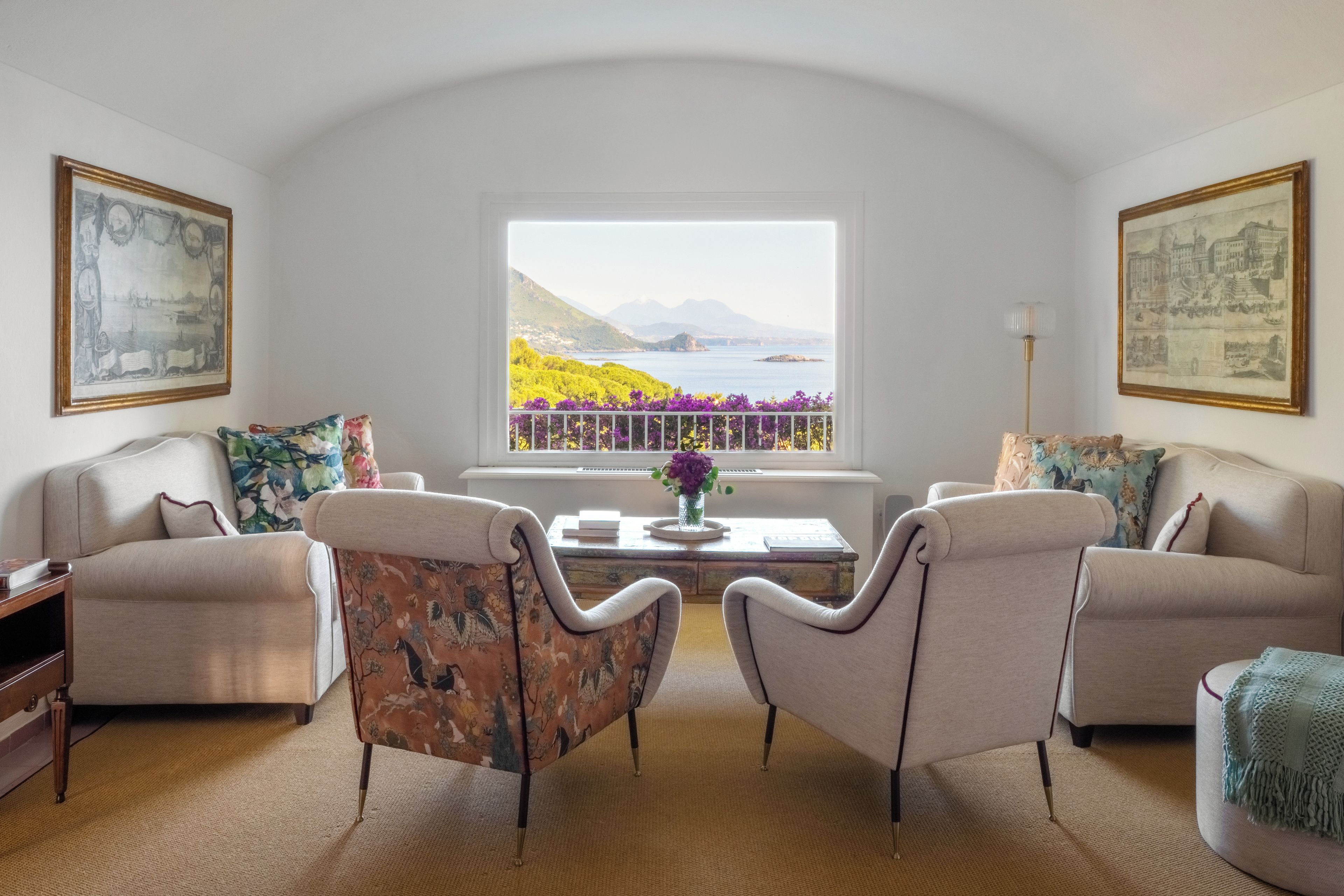 Ein Wohnzimmer mit zwei Sofas, einem Couchtisch und einem Fenster mit Blick auf ein Gewässer und Berge.