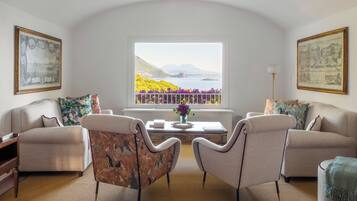 Ein Wohnzimmer mit zwei Sofas, einem Couchtisch und einem Fenster mit Blick auf ein Gewässer und Berge.