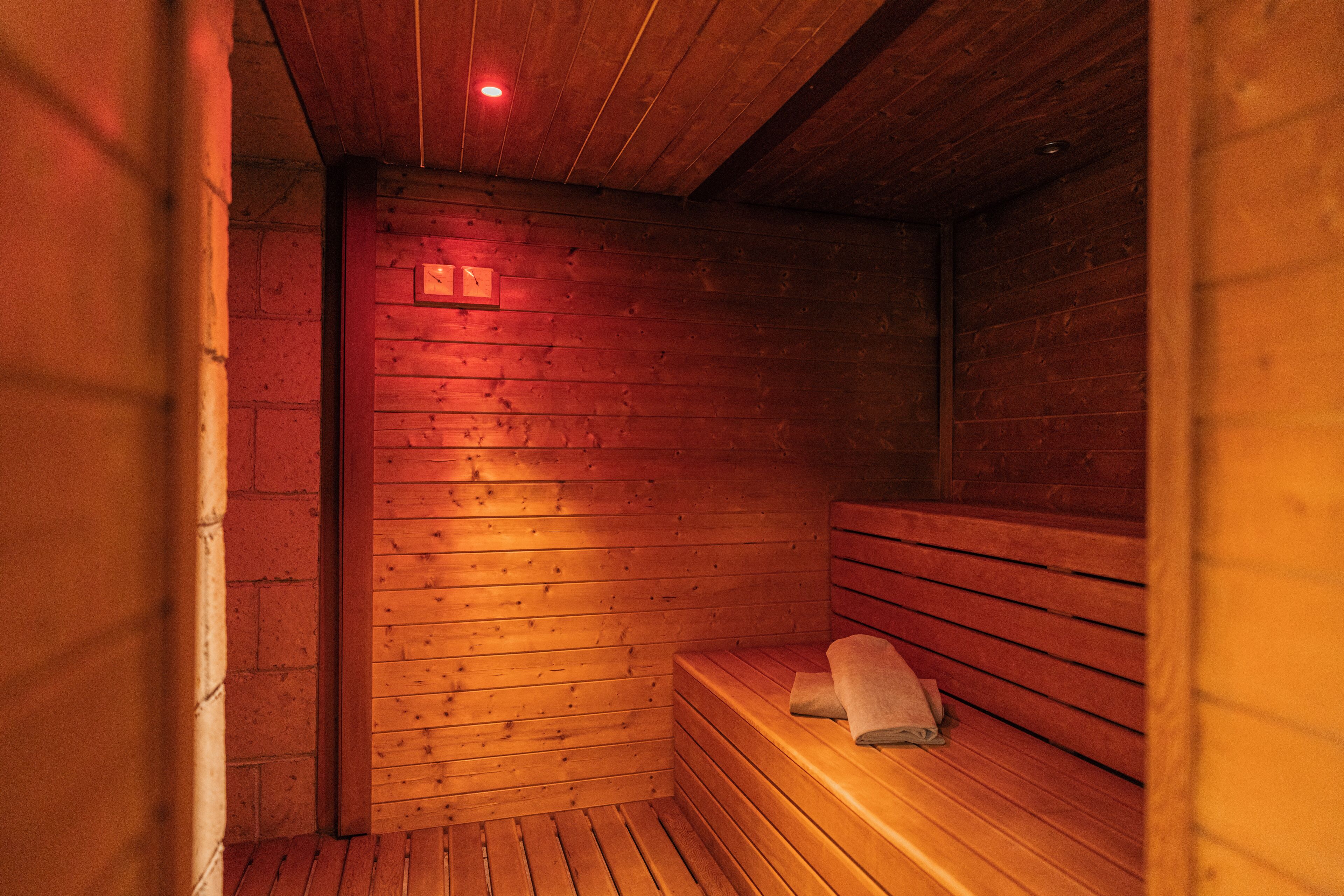 Una sauna con panche in legno e una panca con un asciugamano.