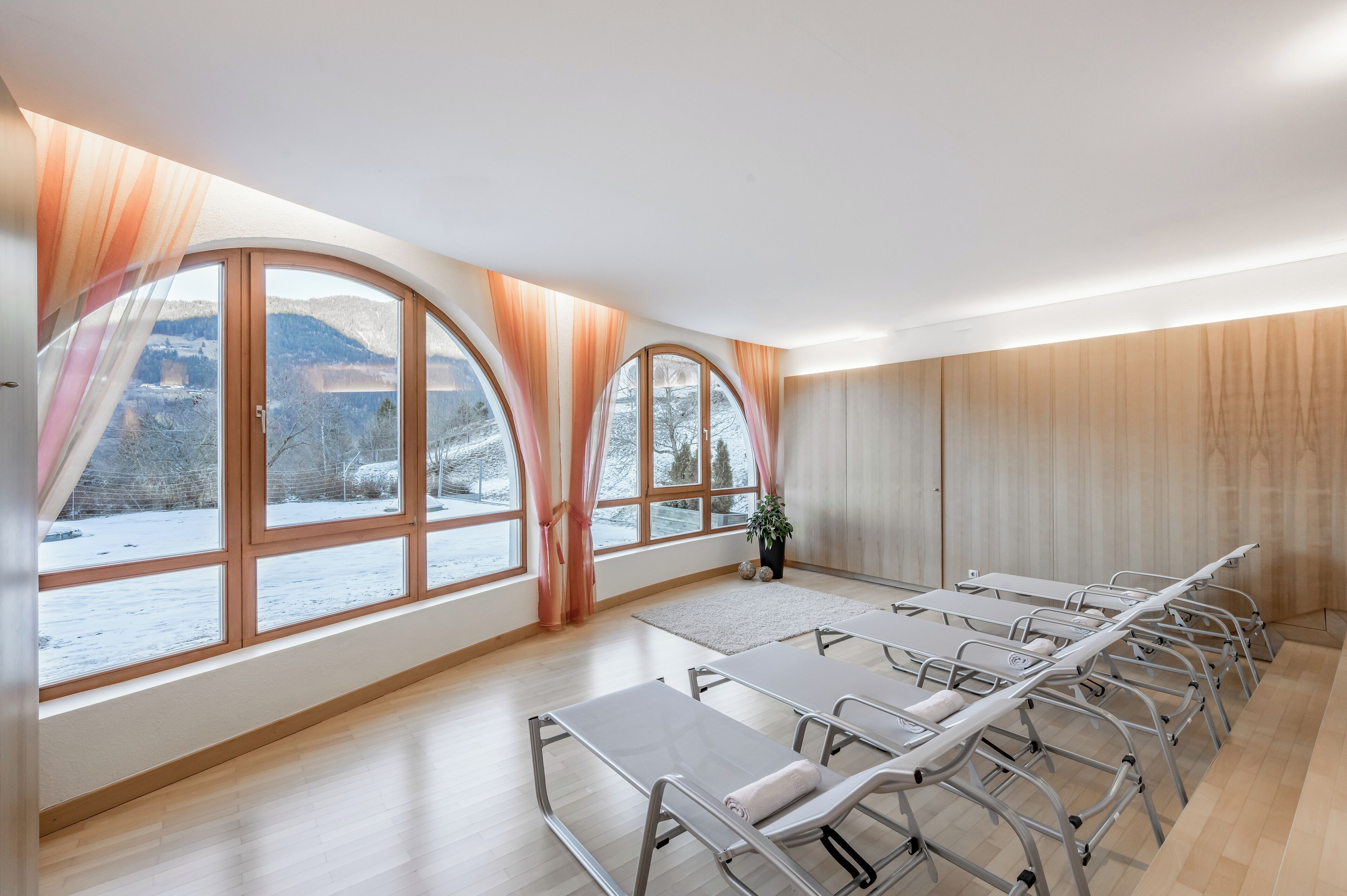 A room with large windows, a long table with chairs, and a view of a snowy landscape.