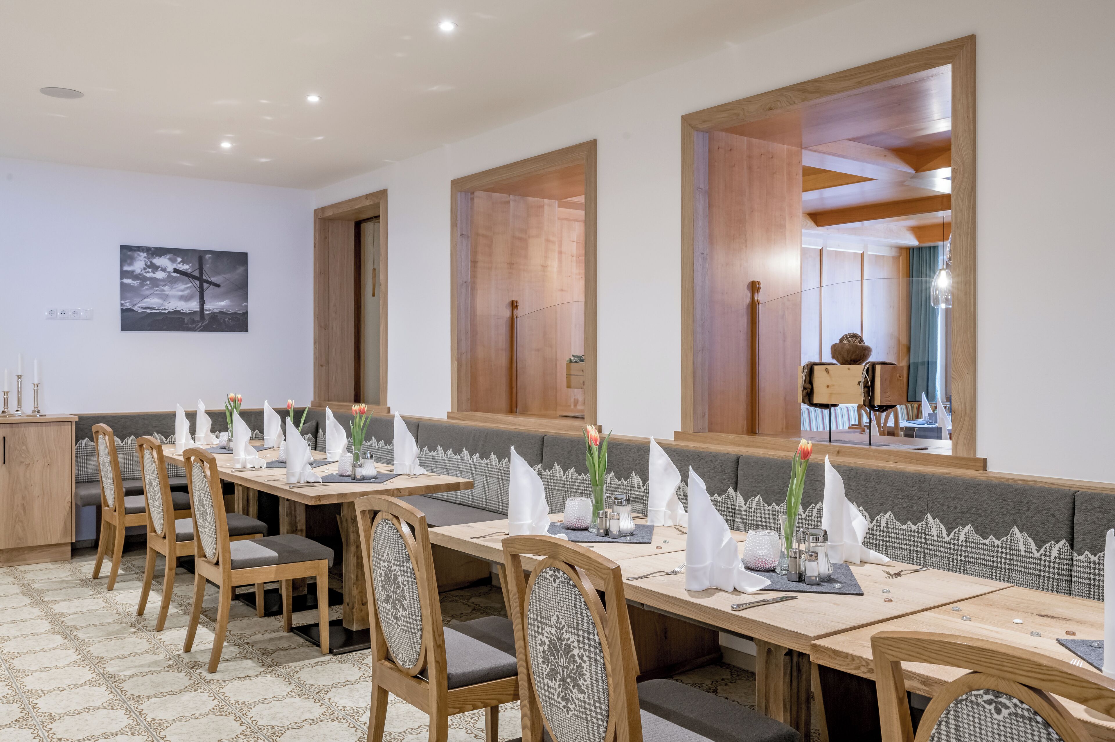 A dining area with a long table set for multiple guests, wooden chairs, and a bench.