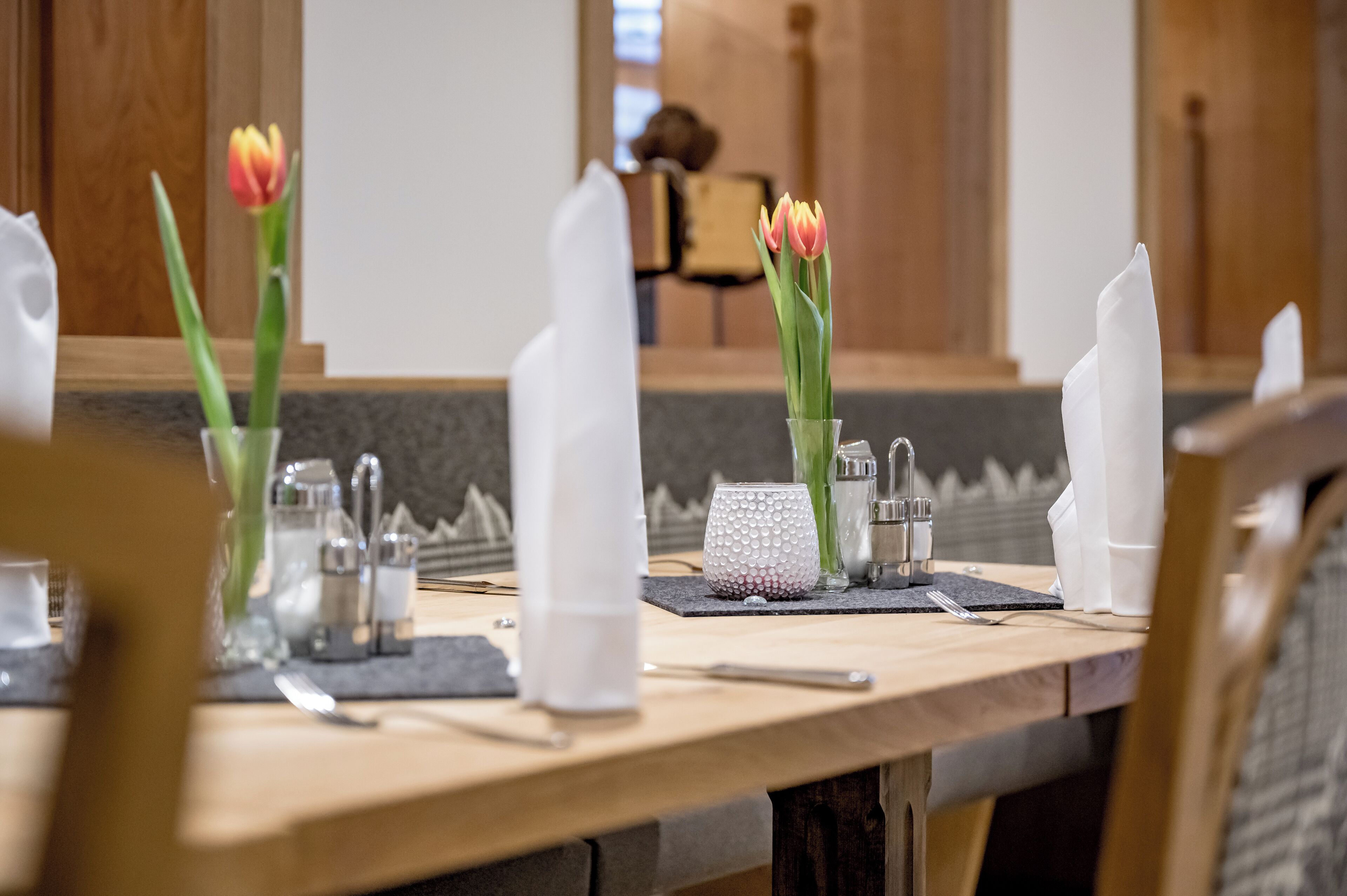 A dining table set with tulips, salt and pepper shakers, a glass, and a napkin holder.