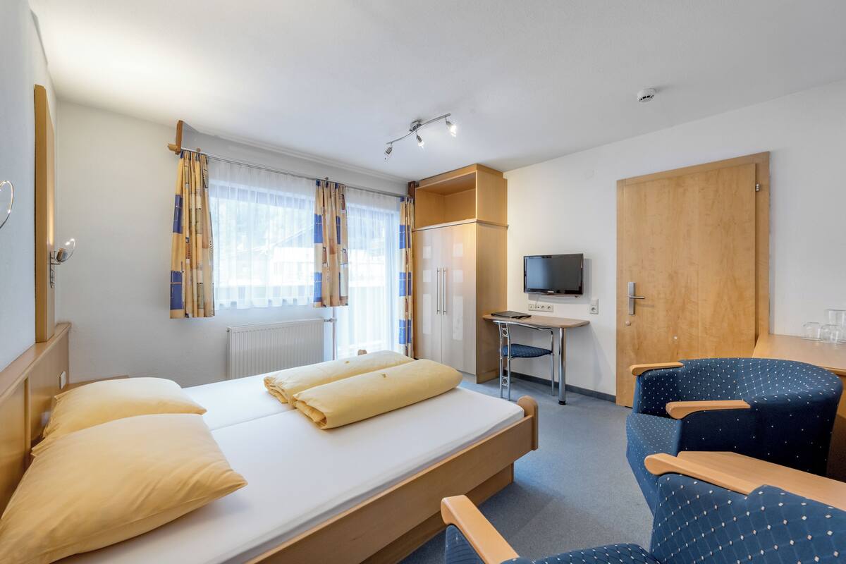 A hotel room with a bed, a desk, a TV, and a wardrobe.