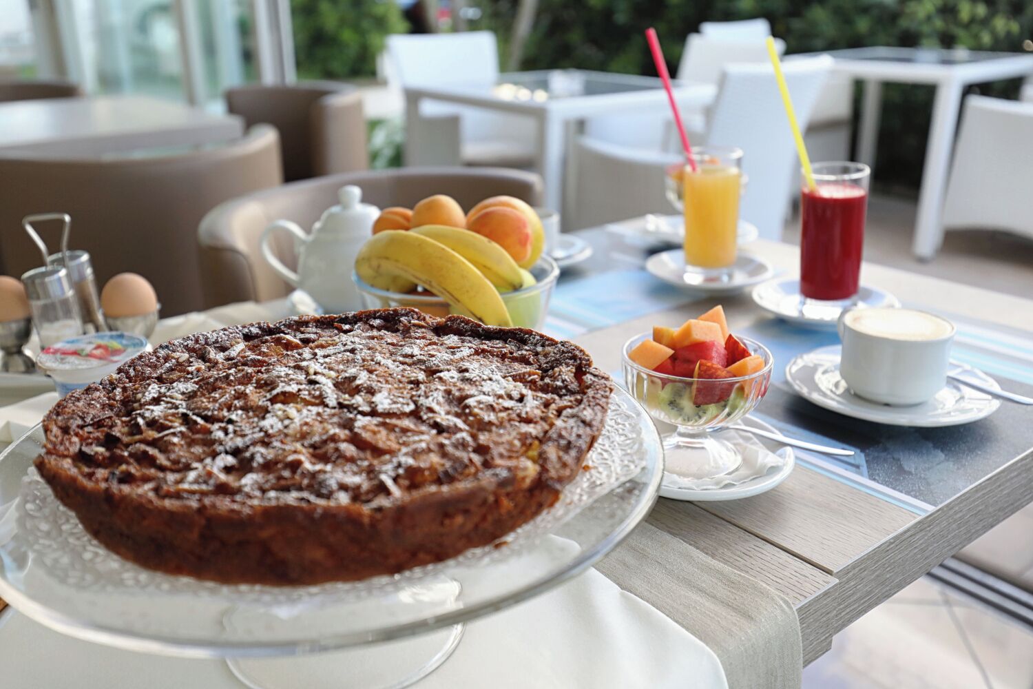 A breakfast setting with a fruit bowl, a coffee cup, and a dessert on a table.