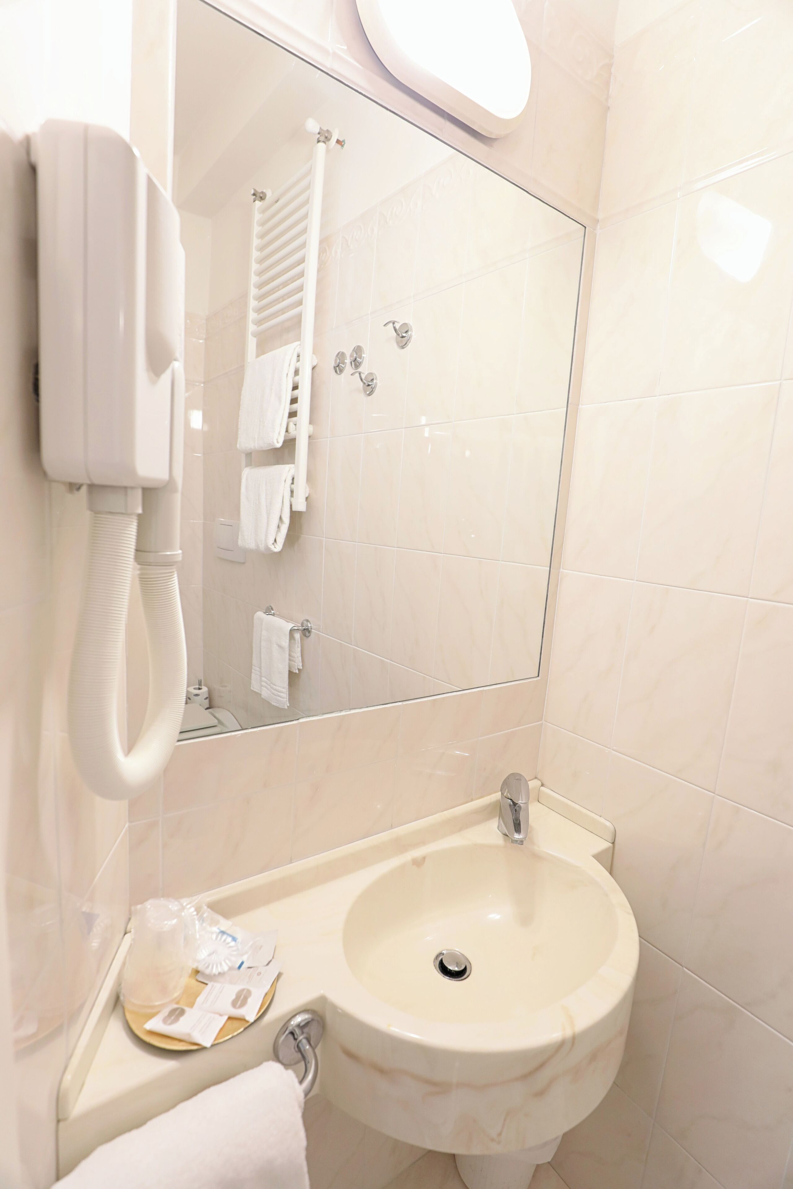 A bathroom with a sink, mirror, and a white telephone.