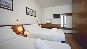 Habitación de hotel con dos camas, televisión, armario de madera y obras de arte en las paredes.