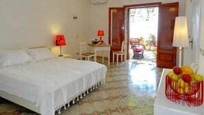 Habitación de hotel con cama, escritorio, silla y una cesta de frutas.