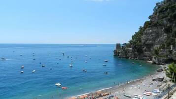 Una playa costera con aguas azules cristalinas, barcos y sombrillas.