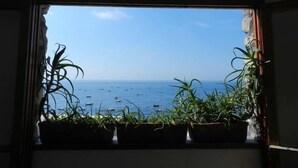 Vista por una ventana que muestra el mar y barcos.